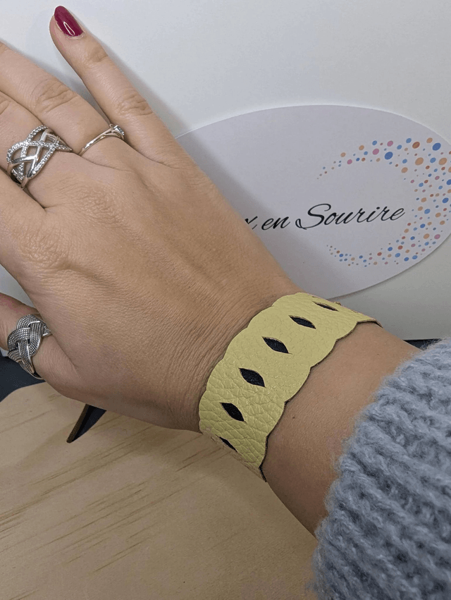 Bracelet manchette en cuir jaune, avec du tissus enduit bleu sombre (résistant), une chaine couleur or. Le fermoir est de couleur or.