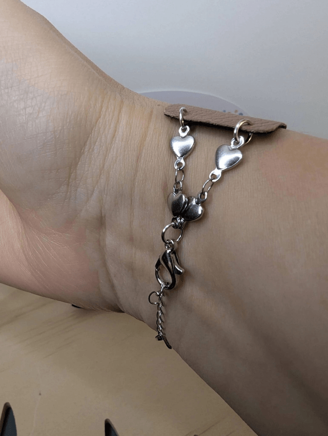 Bracelet manchette en cuir marron clair, avec du tissus enduit noir (résistant), une chaine couleur argent. Le fermoir est  de couleur argent.