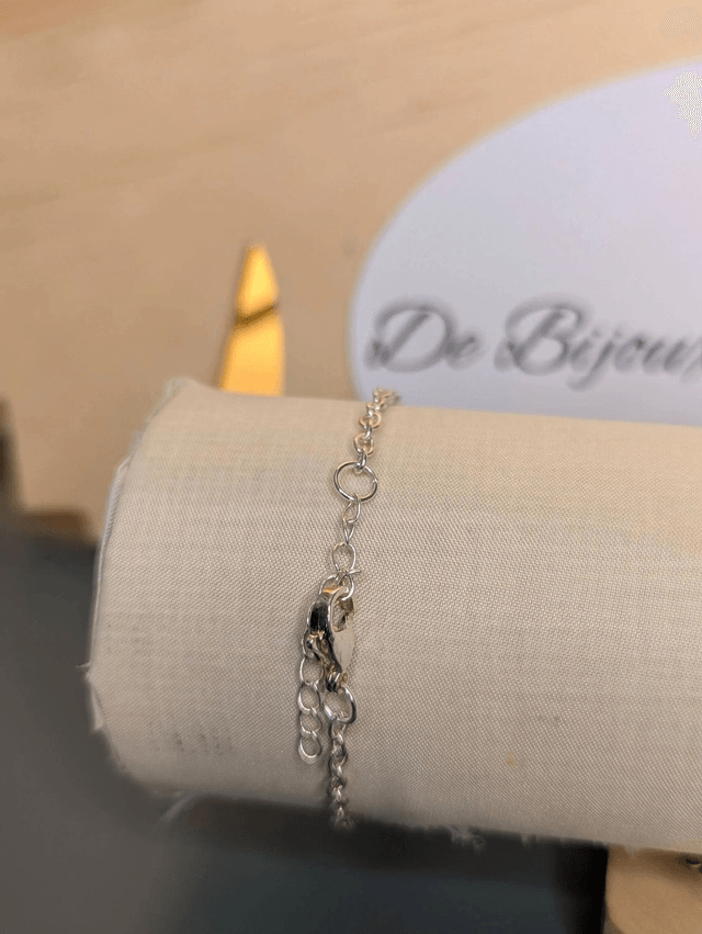 Bracelet avec une chaine de couleur argent, un pendentif en résine avec des fleurs séchés et un papillon en stickers, le fermoir est en argent. 
