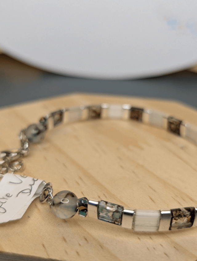 Bracelet en perles plate en verre blanc avec des  perles d'espacement en métal argenté. Le fermoir et la chaine fermoir sont en argent.