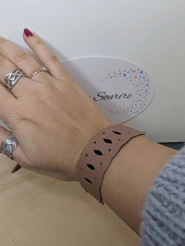 Bracelet manchette en cuir marron clair, avec du tissus enduit noir (résistant), une chaine dorée. Le fermoir est de couleur or.
