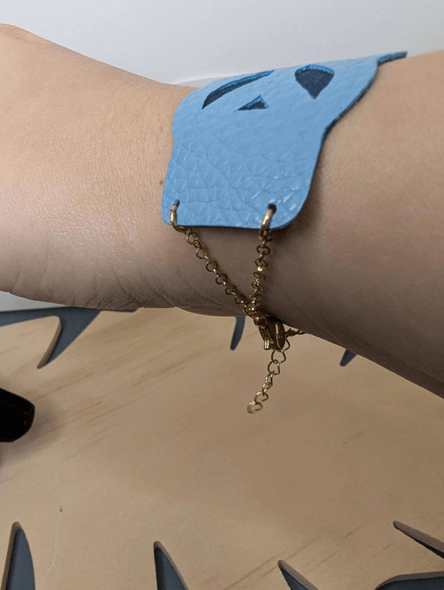 Bracelet manchette en cuir bleu, avec du tissus enduit bleu foncé (résistant), une chaine dorée. Le fermoir est de couleur doré.