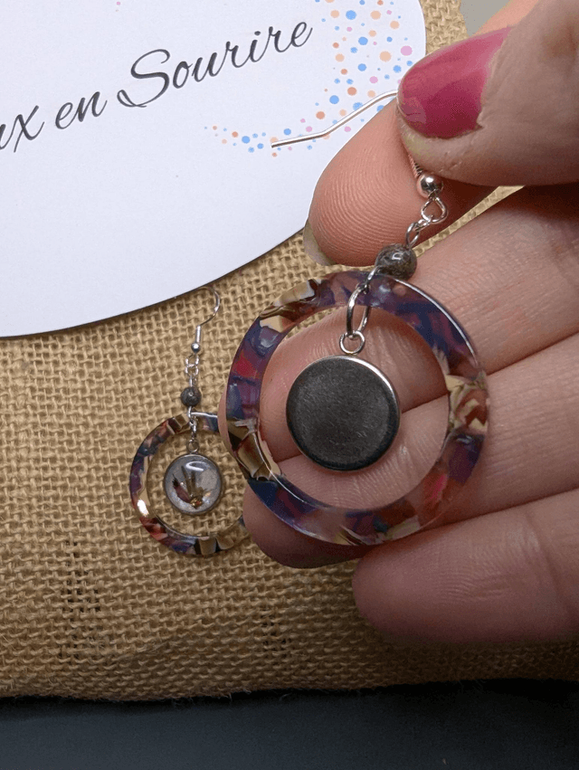 Boucles d'oreilles avec 2 pendentifs en cercle en résine coloré rose et violet, avec des fleurs, et des perle naturelle, le fermoir est en argent. 