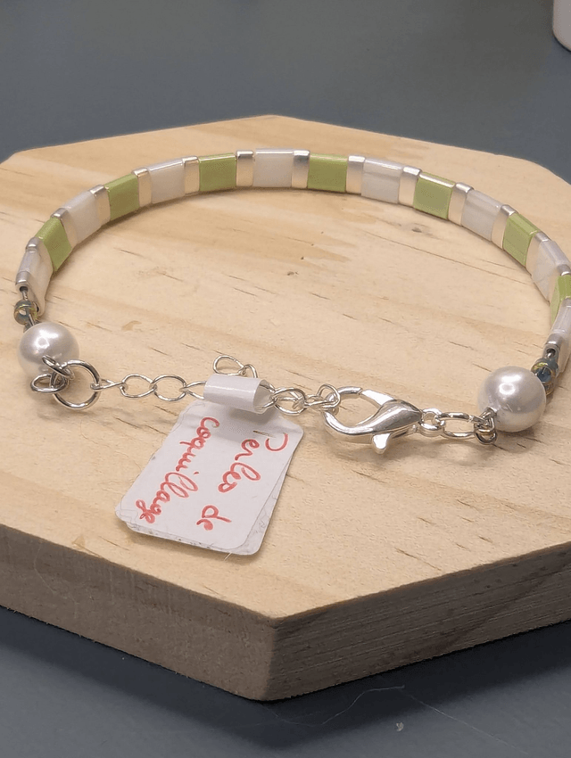 Bracelet en perles plate en verre blanc et vert clair avec des perles d'espacement en métal argenté. Le fermoir et la chaine fermoir sont en argent.