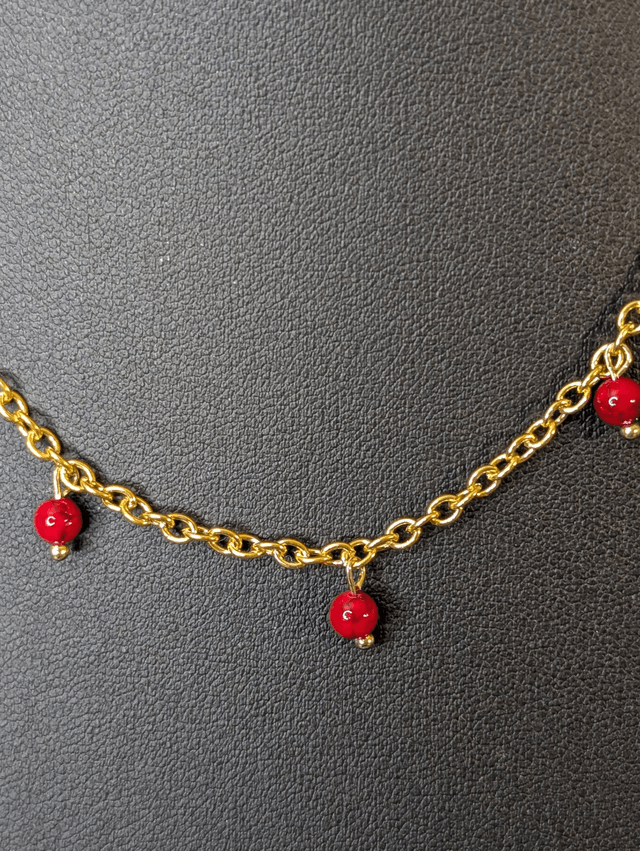 collier court chaine en or fine et des perles naturelles de couleur rouge, la chaine fermoir est de couleur or. 