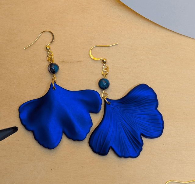 Boucles d'oreilles avec pendentifs en forme de feuilles de couleur bleu métallisé avec des perles de jaspe sédiment de mer.