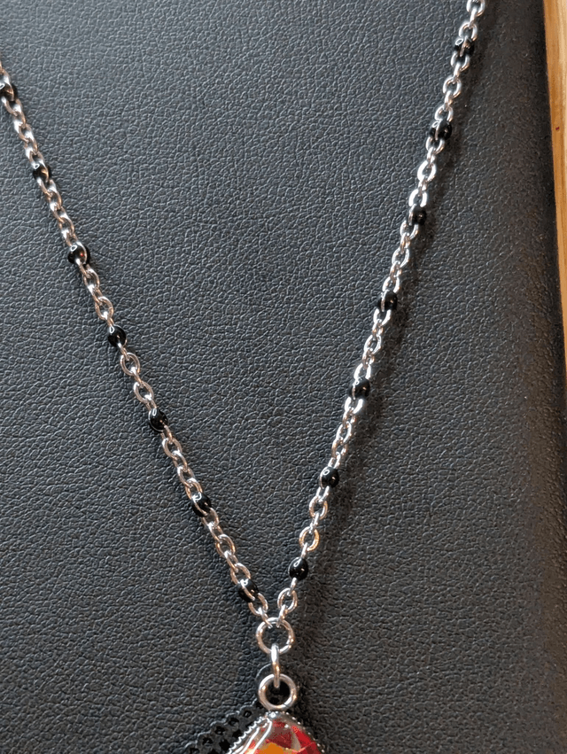 Collier sautoir long avec un pendentif en bois noir et un pendentif en résine rouge, fleurs blanche, chaine en argent. 