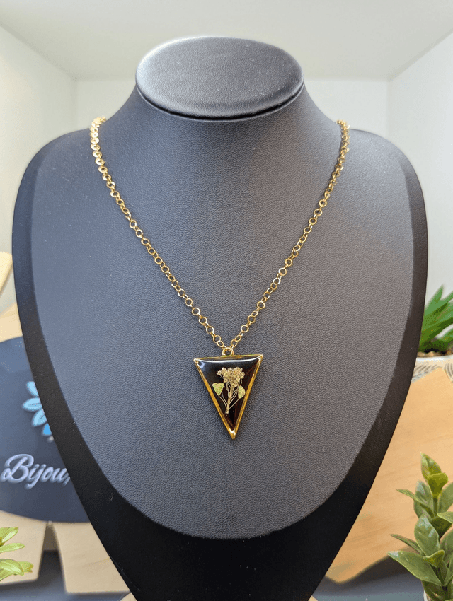 collier mi long de couleur or avec un pendentif en résine rouge et fleur naturelle blanche. 