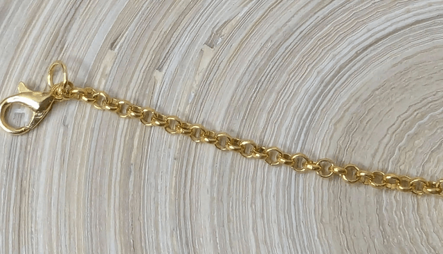 Bracelet avec une chaine de couleur or et un pendentif en résine rose transparent, motif fleur, le fermoir est en or.