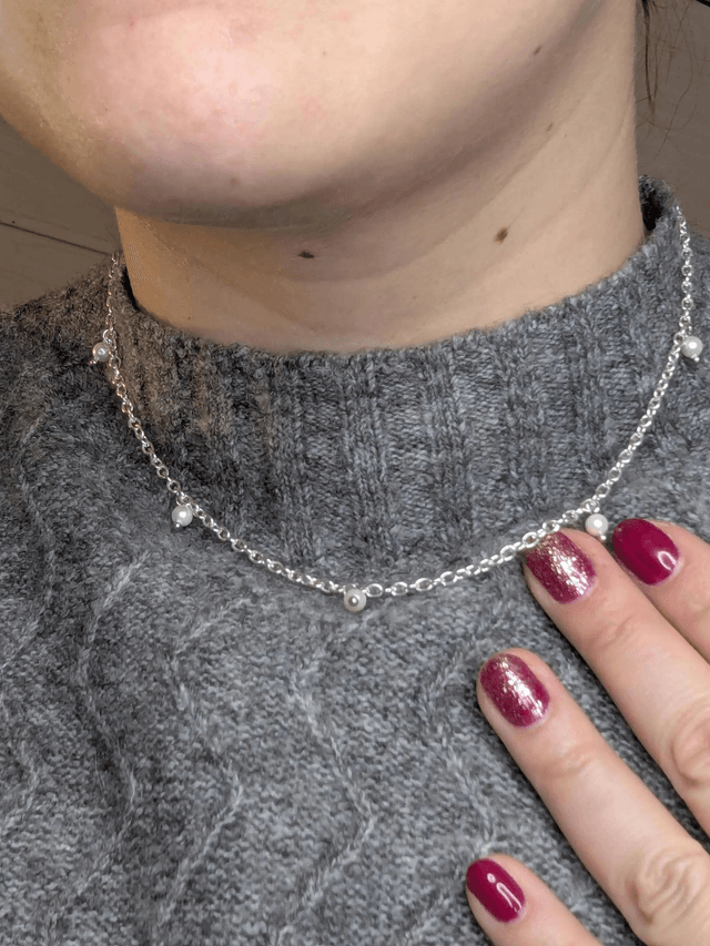 collier court avec une chaine en argent fine et des perles naturelles de coquillage blanc, la chaine fermoir est de couleur argenté. 