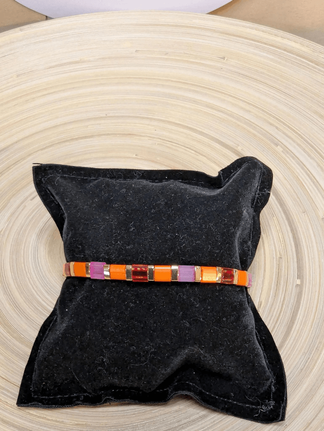 Bracelet avec des perles plate en verre rose, orange et des petites en métal doré. Le fermoir et la chaine fermoir sont en or.