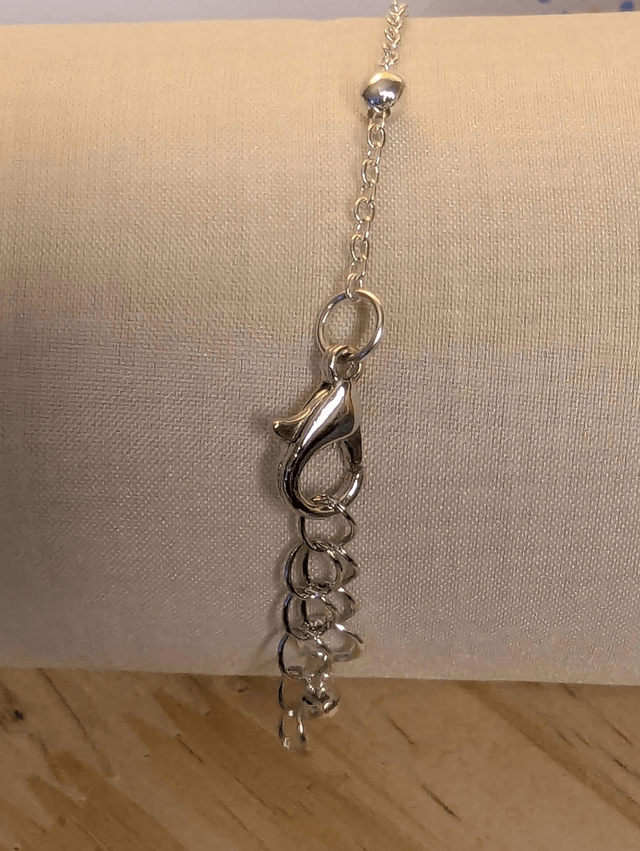 Bracelet avec une chaine de couleur argent, un pendentif résine rose et jaune avec fleurs, le fermoir est en argent. 