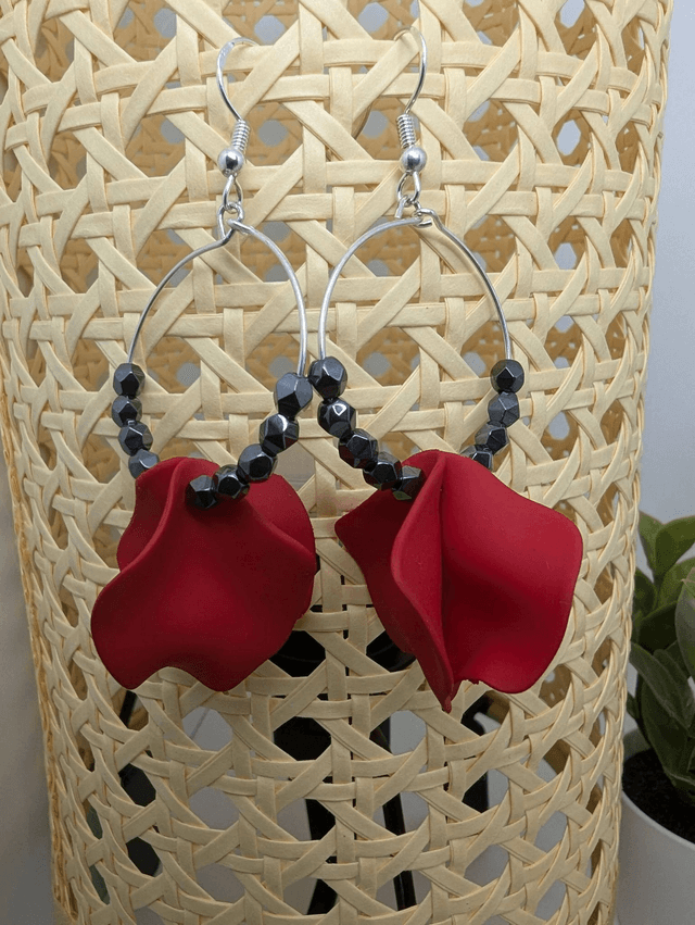 Boucle d'oreille en perles naturelles d'hématite noire et des breloque en forme de pétales en acrylique rouge. 