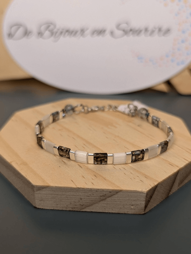 Bracelet en perles plate en verre blanc avec des  perles d'espacement en métal argenté. Le fermoir et la chaine fermoir sont en argent.