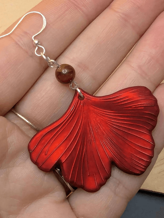 Boucles d'oreilles pendentifs en forme de feuilles, de couleur rouge métallisé avec des perles de cloisonne rouge et marron. 