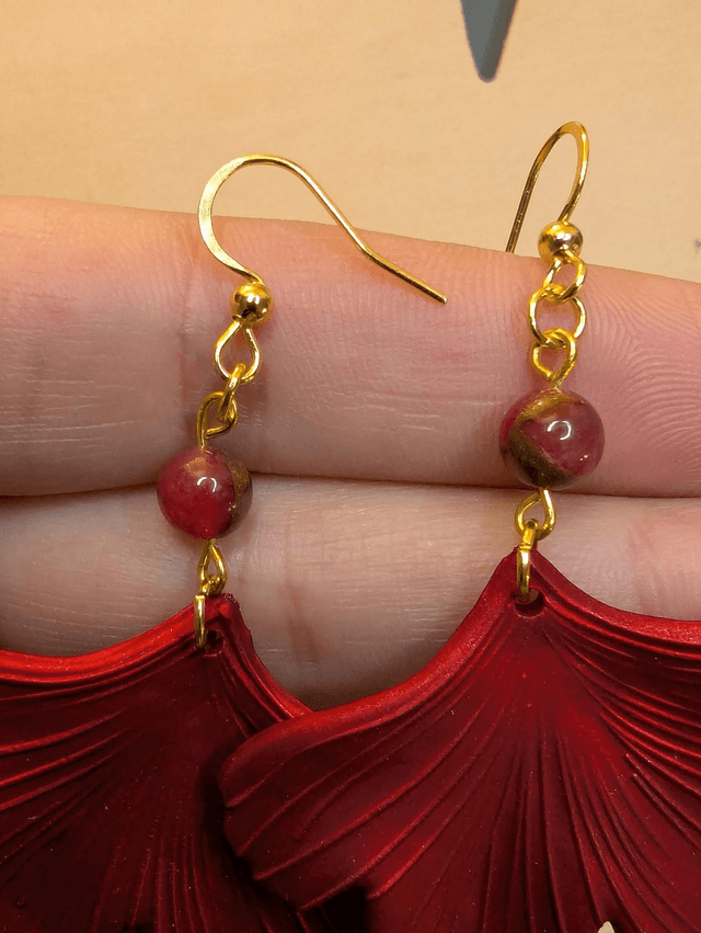 Boucles d'oreilles avec pendentifs en forme de feuilles de couleur rouge métallisé avec des perles de cloisonne rouge et marron.