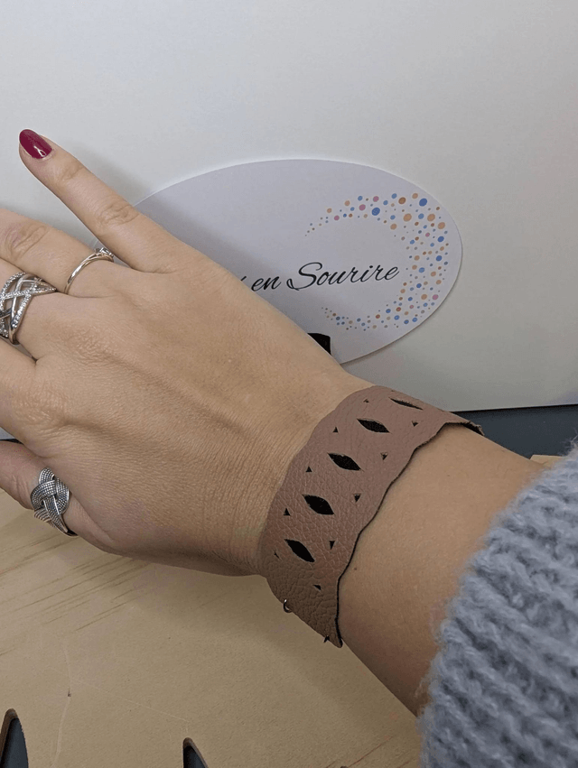 Bracelet manchette en cuir marron clair, avec du tissus enduit noir (résistant), une chaine couleur argent. Le fermoir est  de couleur argent.