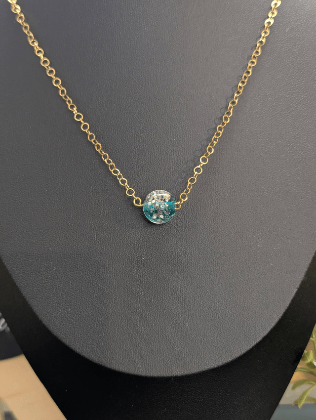 collier mi long avec chaine de couleur or et pendentif en verre de couleur bleu foncé.