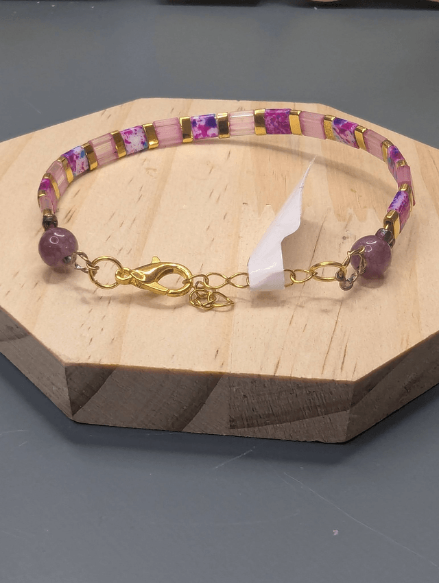 Bracelet avec des perles plate en verre rose et des perles d'espacement en métal doré. Le fermoir et la chaine fermoir sont en or.