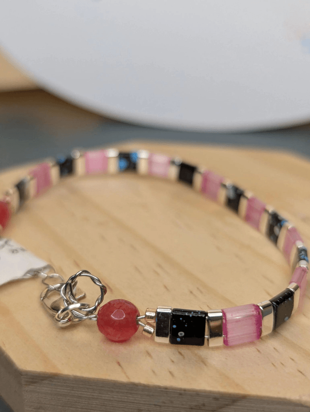 Bracelet en perles plate en verre rose et noire, avec des perles en métal argenté. Le fermoir et la chaine fermoir sont en argent.