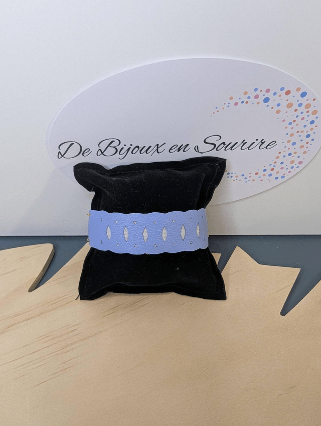 Bracelet manchette en cuir bleu lisse, avec du tissus enduit blanc (résistant), une chaine dorée. Le fermoir est de couleur or. 