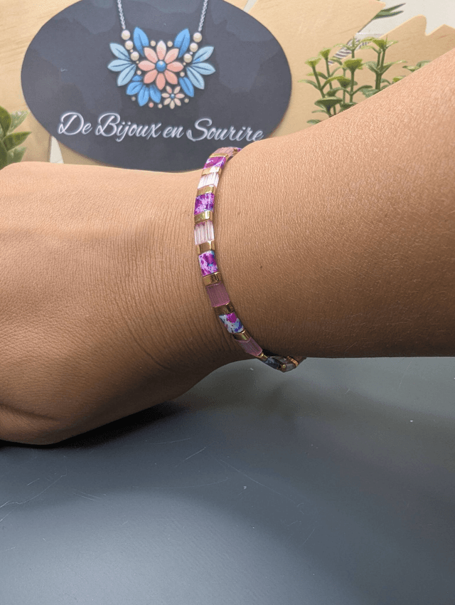 Bracelet avec des perles plate en verre rose et des perles d'espacement en métal doré. Le fermoir et la chaine fermoir sont en or.