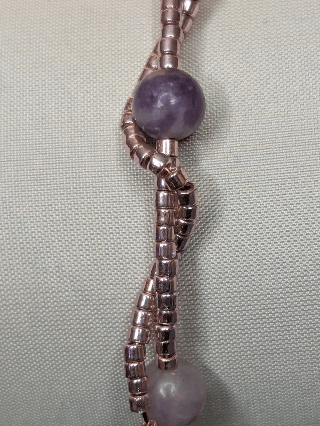Bracelet torsadé violet foncé, avec des perles Miyuki en verre et des perles naturelles violettes sur fil de fer. le fermoir est de couleur or.