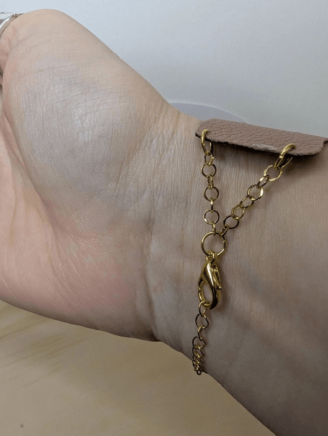 Bracelet manchette en cuir marron clair, avec du tissus enduit noir (résistant), une chaine dorée. Le fermoir est de couleur or.
