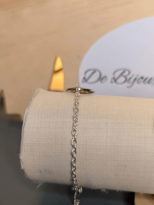 Bracelet avec une chaine de couleur argent, un pendentif en résine avec des fleurs séchés et un papillon en stickers, le fermoir est en argent. 