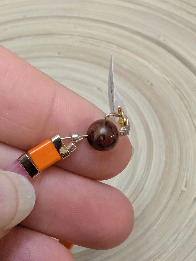 Bracelet avec des perles plate en verre rose, orange et des petites en métal doré. Le fermoir et la chaine fermoir sont en or.