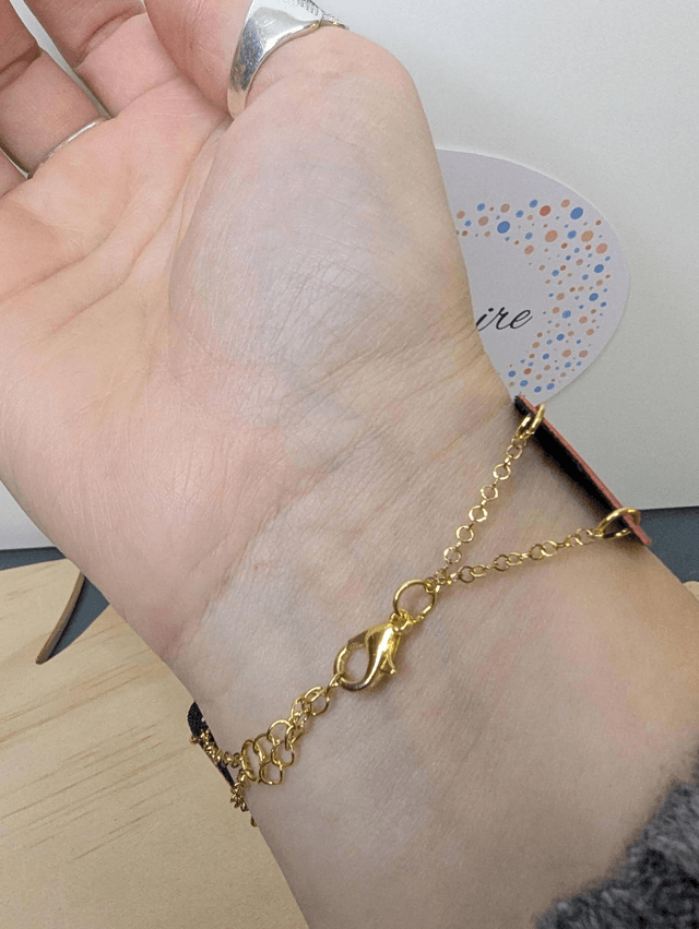 Bracelet manchette en cuir rouge, avec du tissus enduit bleu foncé (résistant), une chaine en or. Le fermoir est de couleur or.