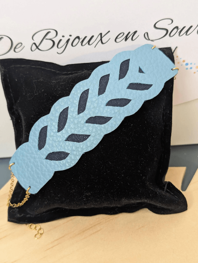Bracelet manchette en cuir bleu, avec du tissus enduit bleu foncé (résistant), une chaine dorée. Le fermoir est de couleur doré.