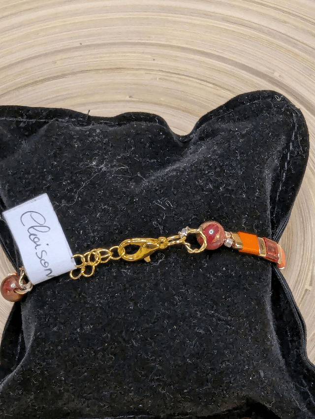 Bracelet avec des perles plate en verre rose, orange et des petites en métal doré. Le fermoir et la chaine fermoir sont en or.