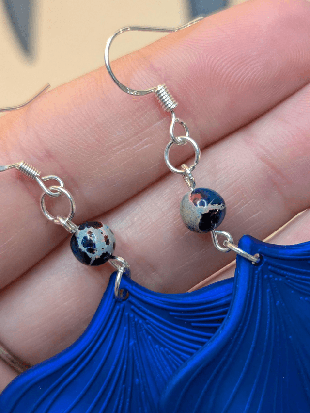 Boucles d'oreilles avec pendentifs en forme de feuilles de couleur bleu métallisé et des perles de jaspe sédiment de mer. 