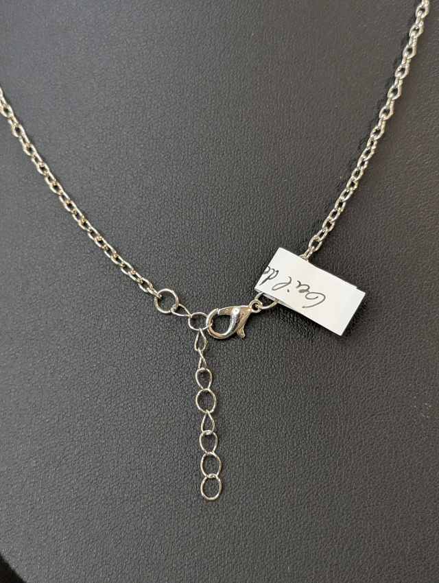 Collier mi long avec une chaine de couleur argent, un pendentif en résine noire et gris pailleté et des perles naturelles rose. 