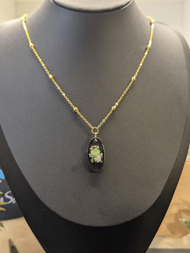 Collier mi long avec une chaine de couleur argent et un pendentif en résine noire avec des fleurs séchés. 