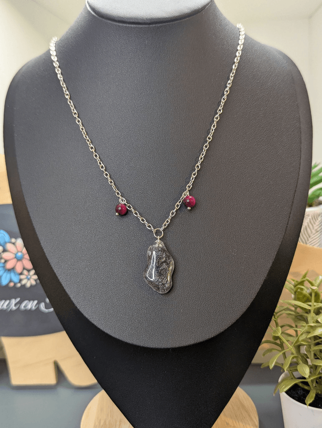 Collier mi long avec une chaine de couleur argent, un pendentif en résine noire et gris pailleté et des perles naturelles rose. 