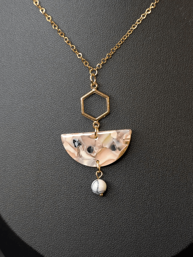 Collier mi long avec une chaine de couleur or et un pendentif en résine rose et noir et un pendentif en métal doré.