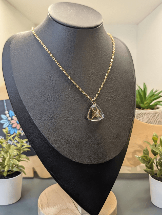 Collier avec pendentif en résine transparente te marron en forme de triangle.