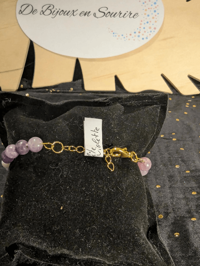 Bracelet en perles de lépidolite violette, et des perles d'espacement violette. Le fermoir et la chaine fermoir sont de couleur or.