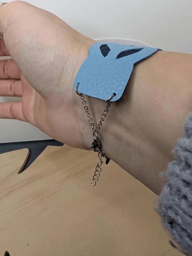 Bracelet manchette en cuir bleu, avec du tissus enduit bleu foncé (résistant), une chaine argentée. Le fermoir est de couleur argent.