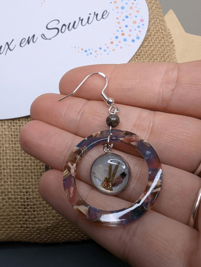 Boucles d'oreilles avec 2 pendentifs en cercle en résine coloré rose et violet, avec des fleurs, et des perle naturelle, le fermoir est en argent. 