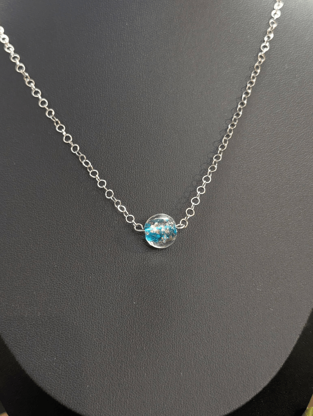 collier mi long avec chaine de couleur argent et pendentif en verre de couleur bleu clair. 