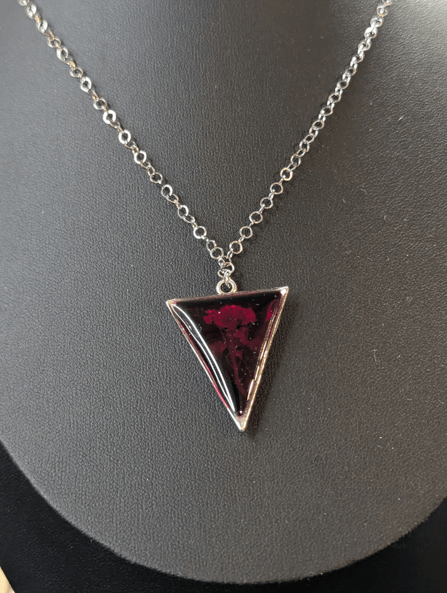 collier mi long de couleur argent avec un pendentif en résine rouge et fleur naturelle blanche. 