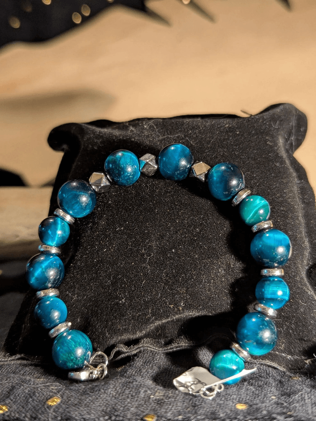 Bracelet en perles d'œil de tigre bleu et des perles d'espacement plate en argent. Le fermoir et la chaine fermoir sont en argent.