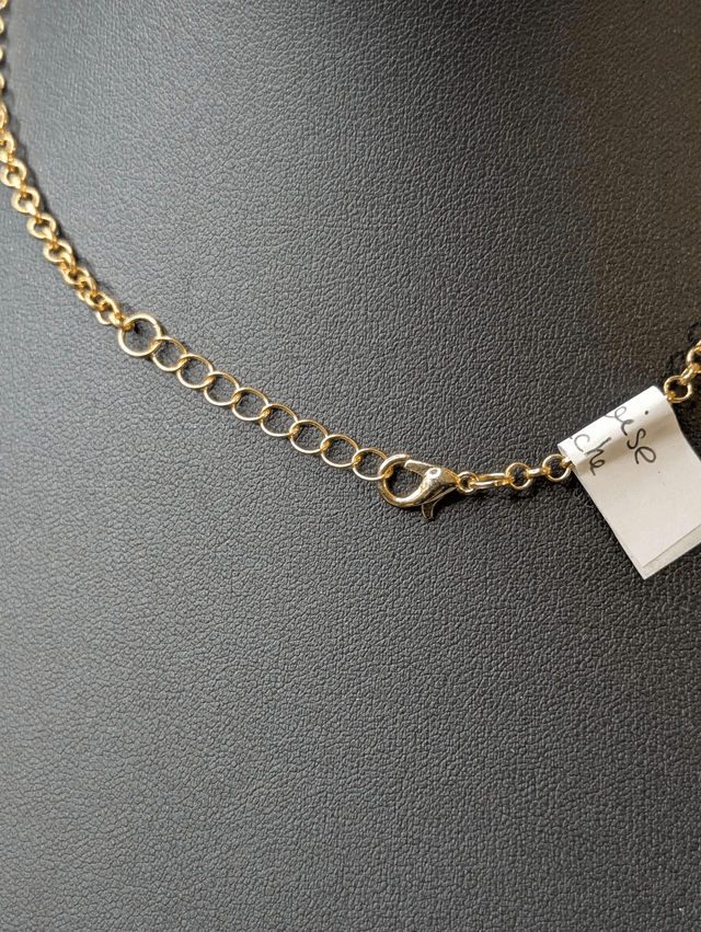 Collier mi long avec une chaine de couleur or et un pendentif en résine bleu et blanc, et un pendentif en métal doré. 