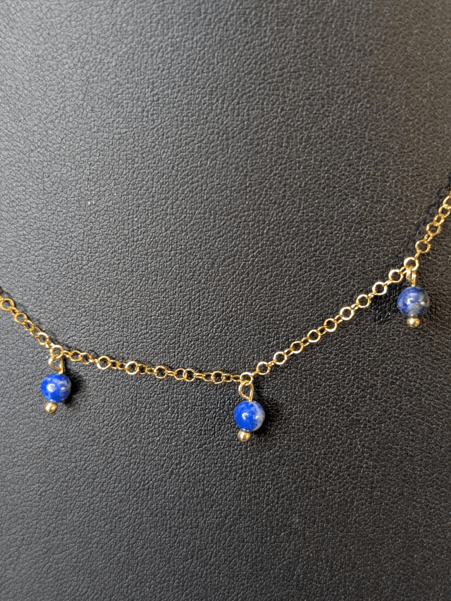 collier court avec une chaine en or fine et des perles naturelles de couleur bleu, la chaine fermoir est de couleur or. 