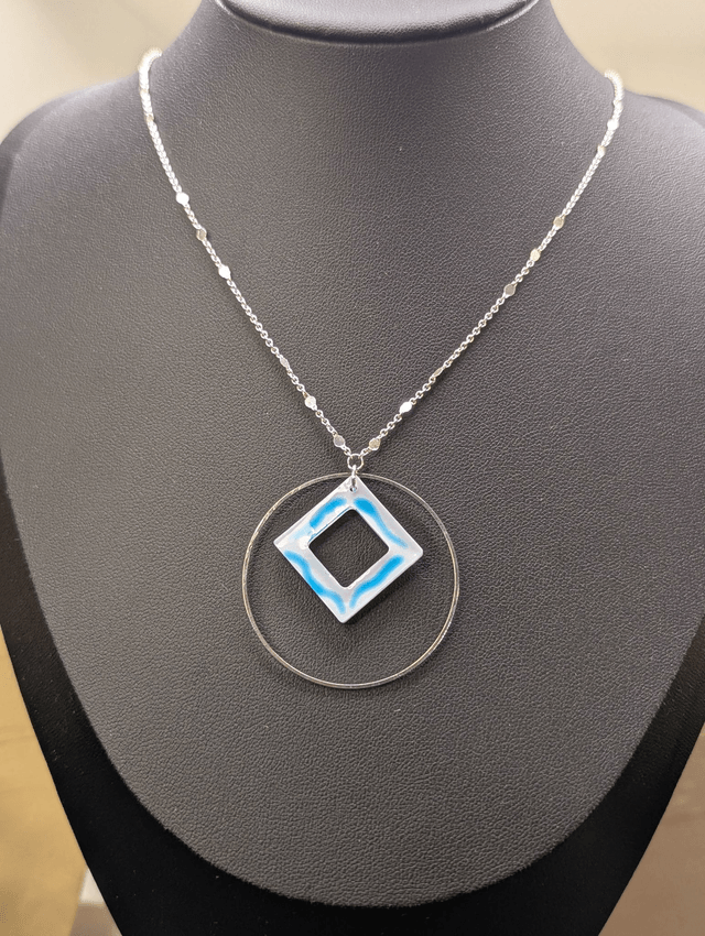 Collier court avec une chaine de couleur argent, un pendentif avec carré en résine et un cercle en métal argenté. 