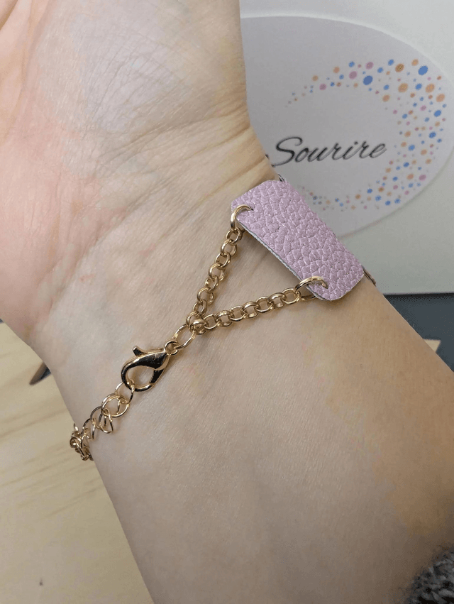 Bracelet manchette en cuir rose poudré, avec du tissus enduit blanc (résistant), une chaine couleur or. Le fermoir est de couleur or.