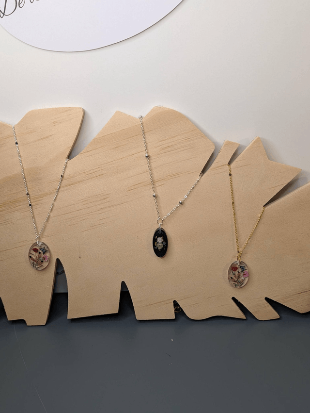 Collier mi long avec une chaine de couleur argent et un pendentif en résine noire avec des fleurs séchés. 
